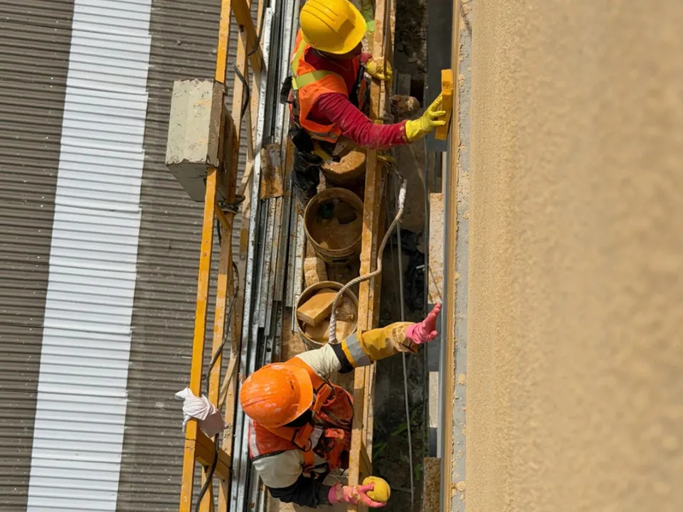 Cuadrilla con casco trabajando en andamio sobre la fachada de un edificio